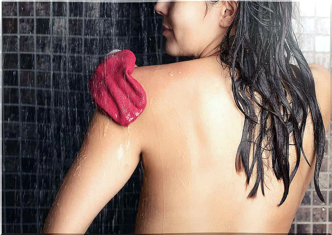 A woman exfoliating her skin in the shower.