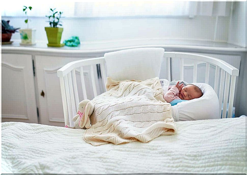 Baby sleeps in bed close to mother