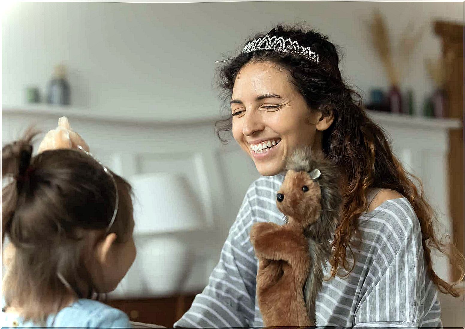 A mother and her daughter are playing with dolls.