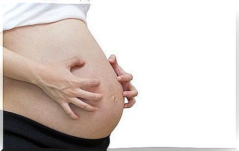 Pregnant woman scratches belly