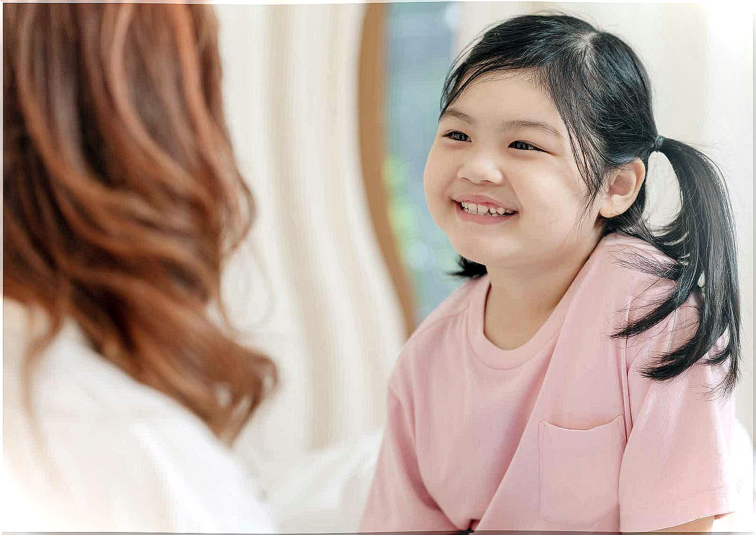 A young girl smiles proudly at her mother.