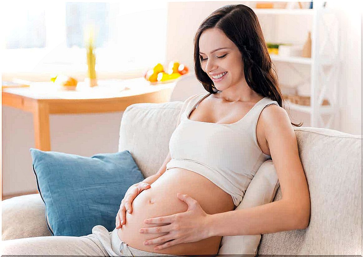 A woman smiling at her pregnant belly.