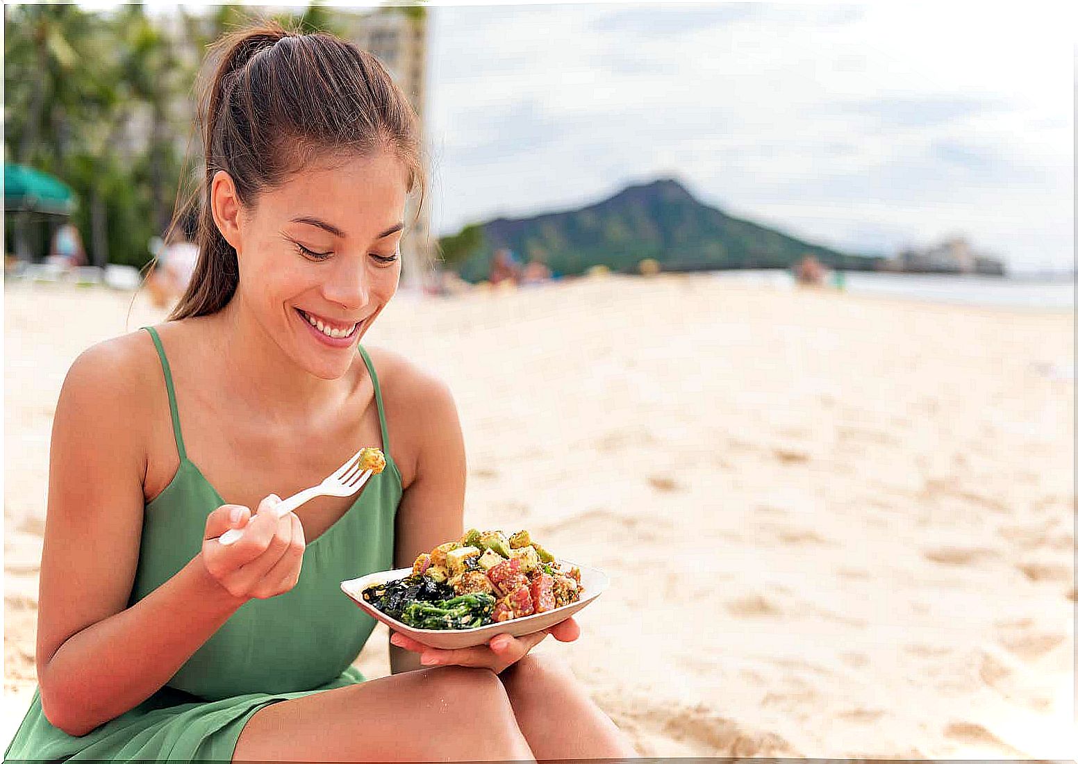 Woman on the beach eating healthy food prepared at home to avoid food poisoning.