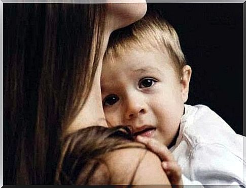 Scared toddler sitting with his mother