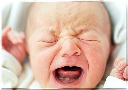 Baby cries with closed eyes and open mouth