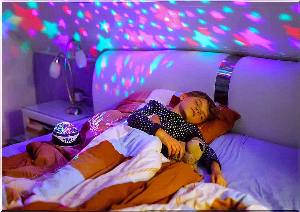 A child sleeping next to a star projector.