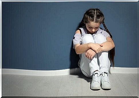 sad girl sitting against a wall